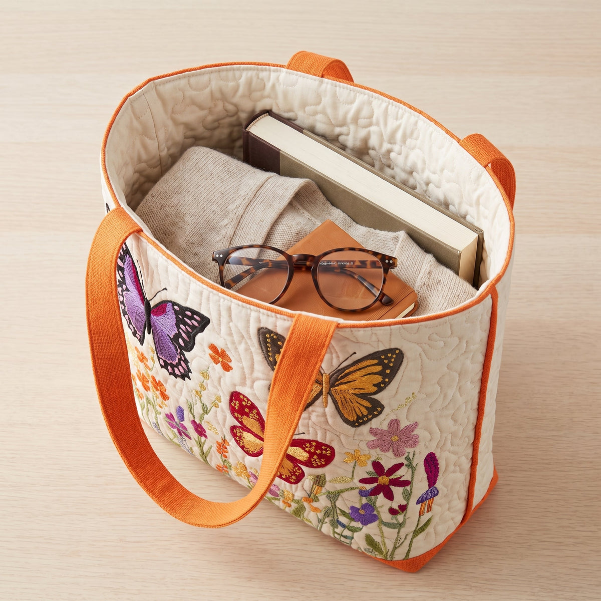 Butterfly Flower Garden Quilted Tote Bag — packed with a hardback book, a folded cardigan and reading glasses
